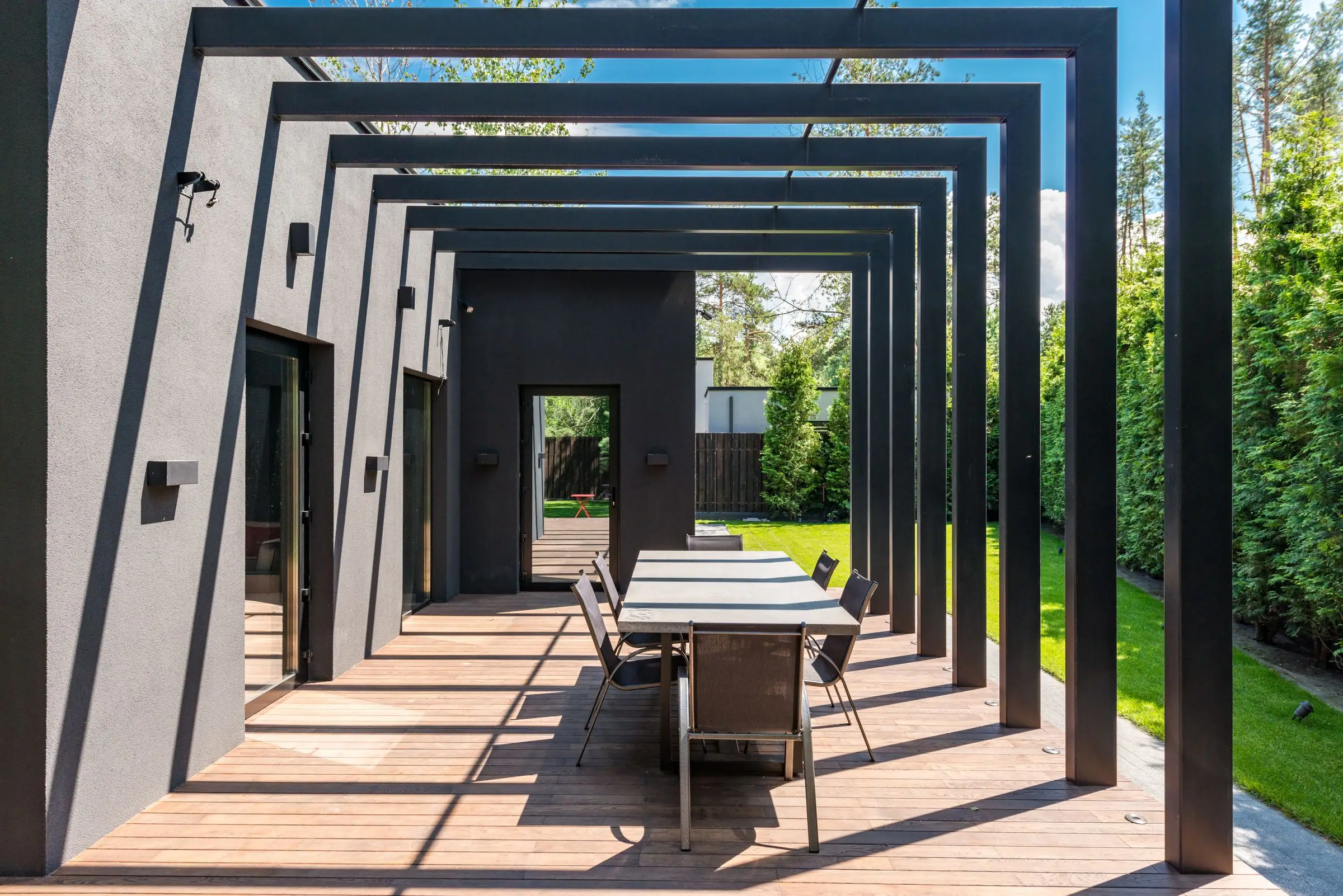 Modern black pergola over a long outdoor dining table