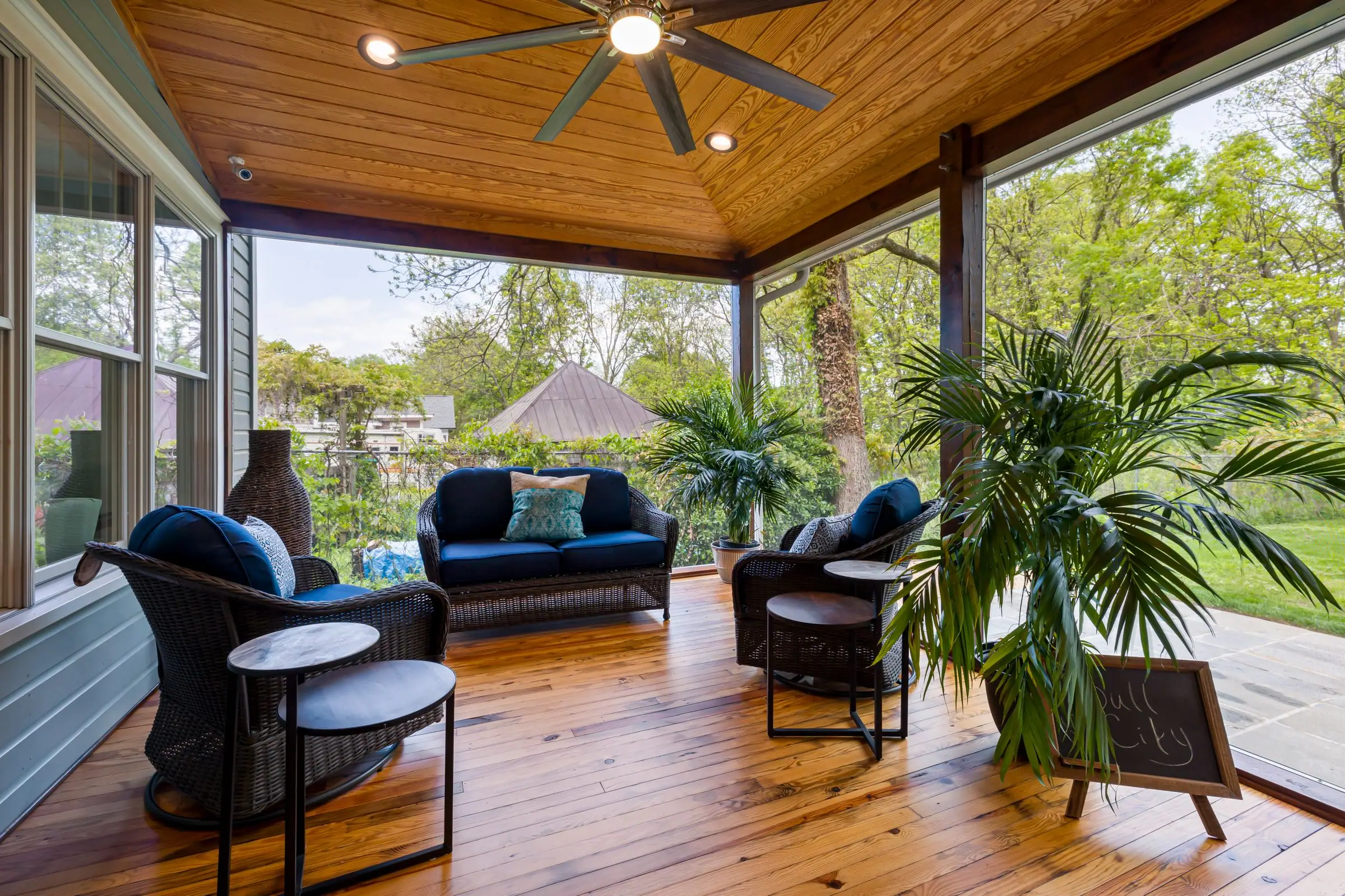 Covered patio with a wood plank ceiling, ceiling fans and wicker seating