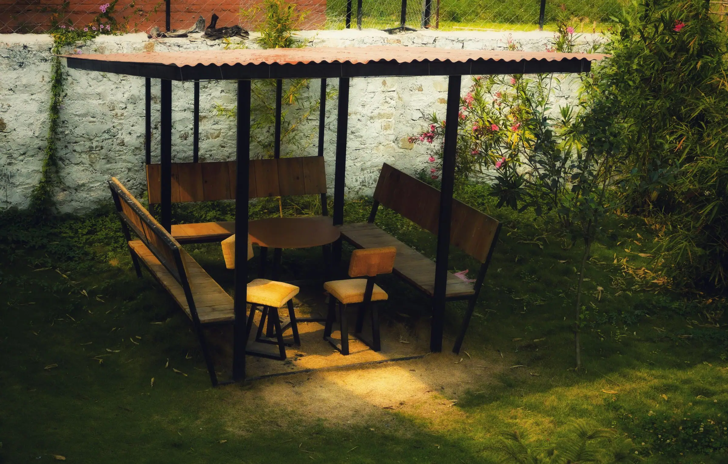 Freestanding shade canopy over benches and a table in a garden